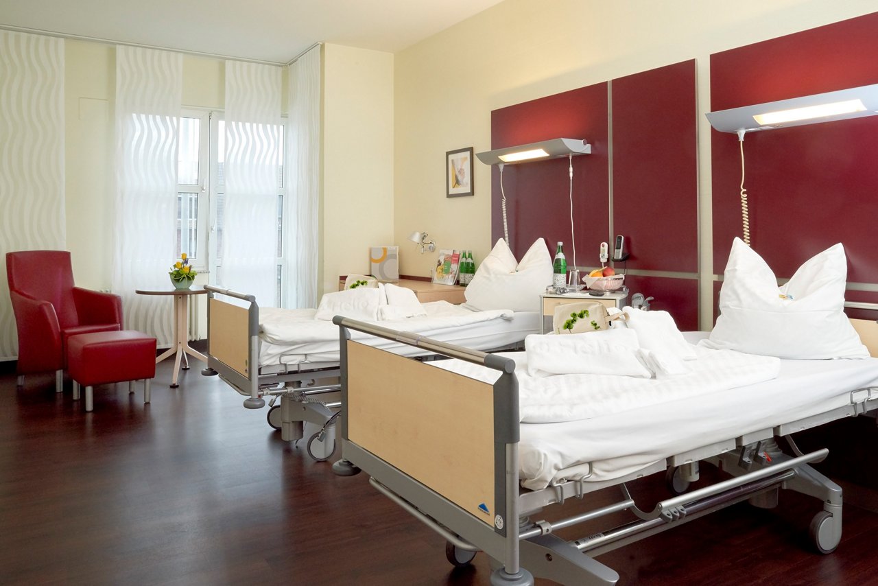 Patientenzimmer der Privatklinik Zweibett mit  Bett, Lounge und Nachttisch