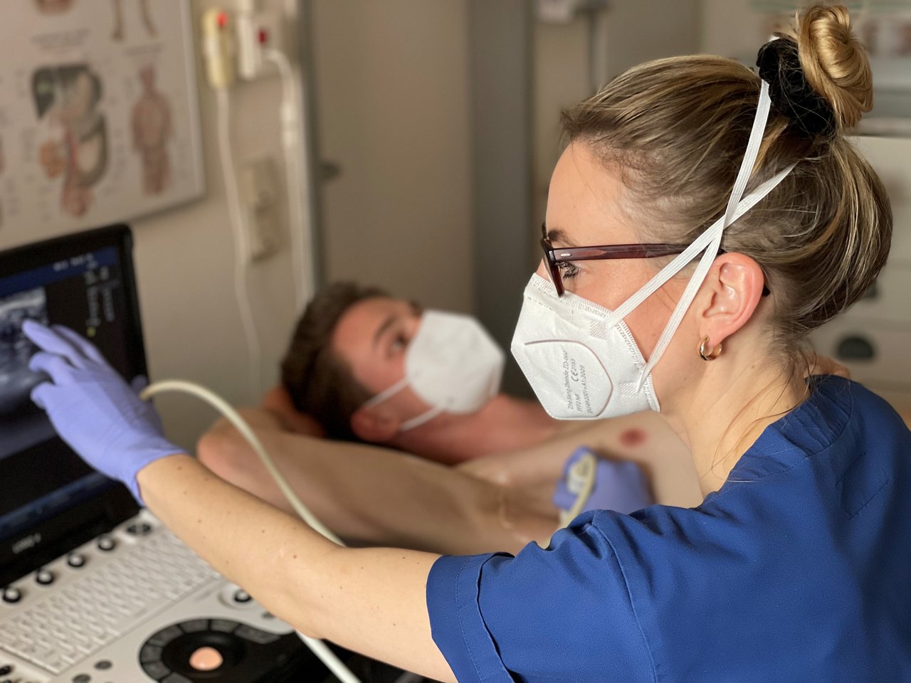 Ärztin untersucht mit Sonografie-Gerät Achsel von Patient 