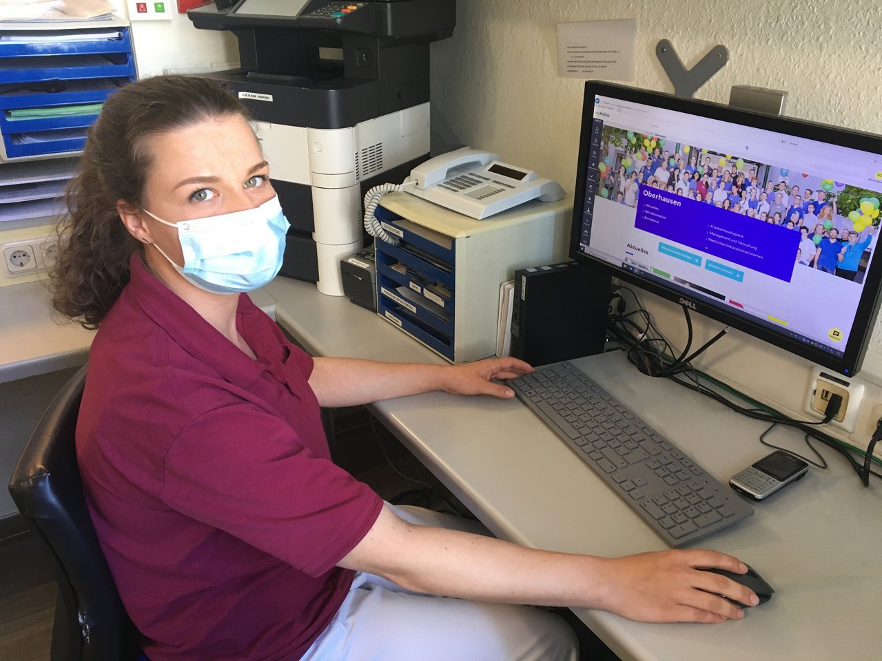 Stationssekretärin sitzt am Computer im Stationsstützpunkt