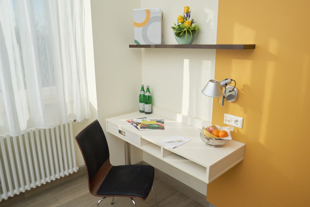 Schreibtisch der Wahlleistung mit Speisekarte, Notizblock, Wasser, Stuhl und Obstkorb