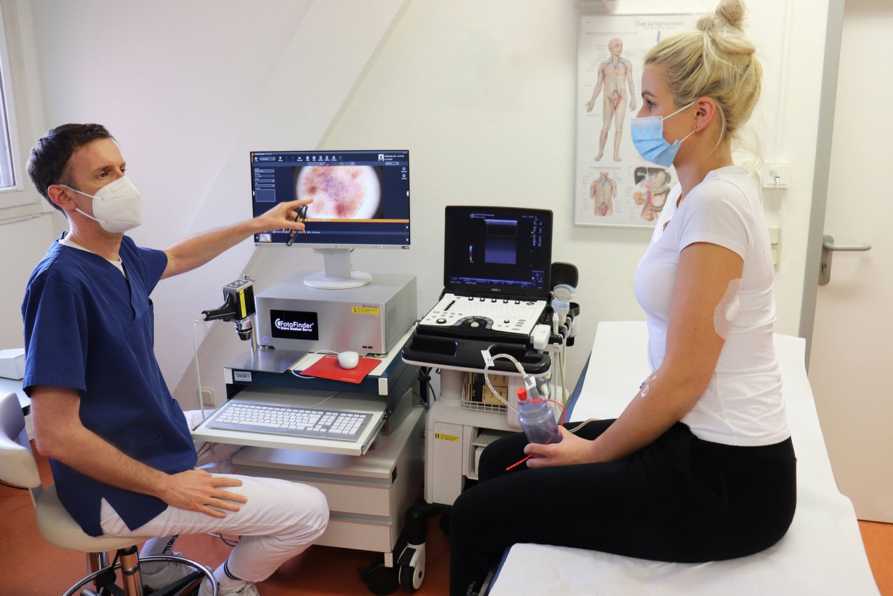 Arzt zeigt Hautkrebs-Patientin Melanom auf Bildschirm 