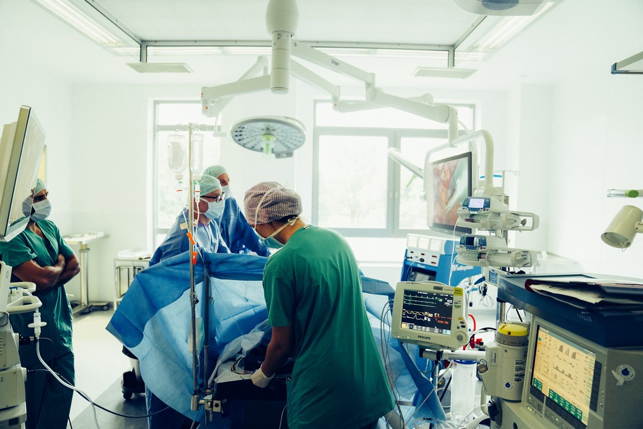 Zwei Ärzte operieren, eine OTA steht am Kopf der zu operierenden Person