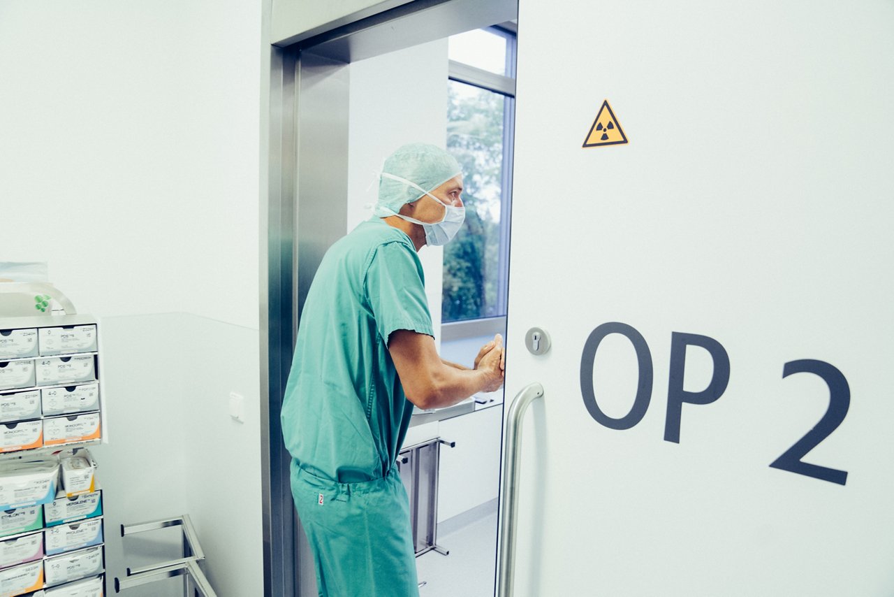 Arzt steht während der Händedesinfektion in der Tür zum OP