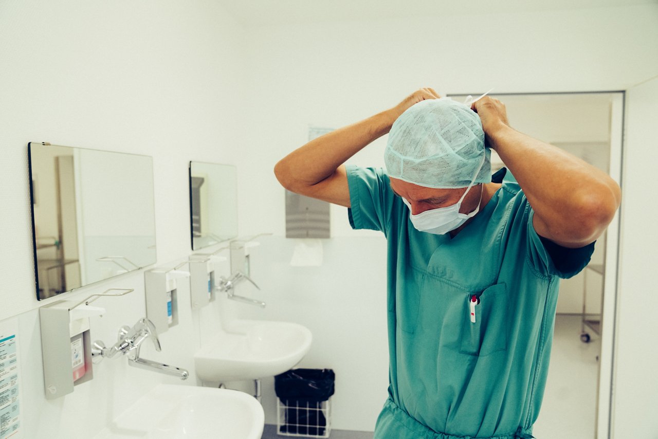 Arzt legt sich einen Mundschutz an