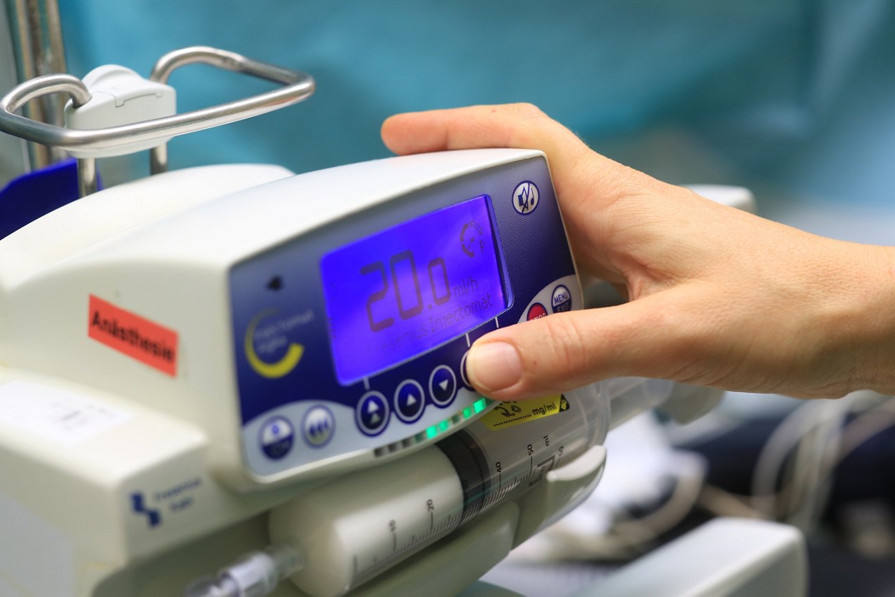 Hand die einen bestückten Perfusor im orthopädischen Operationssaal bedient