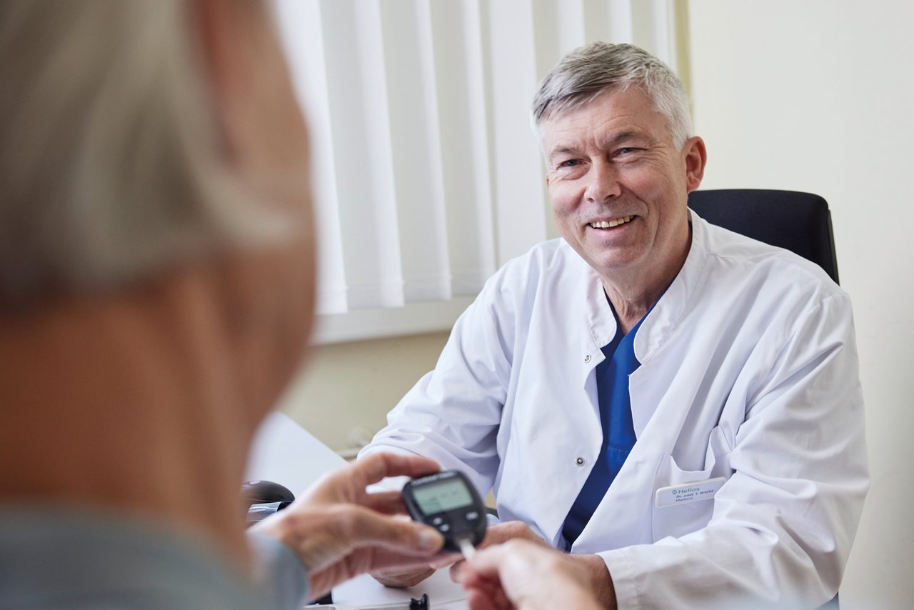 Freundlicher Arzt berät Patientin in Sachen Diabetes und erklärt die Blutzuckermessung