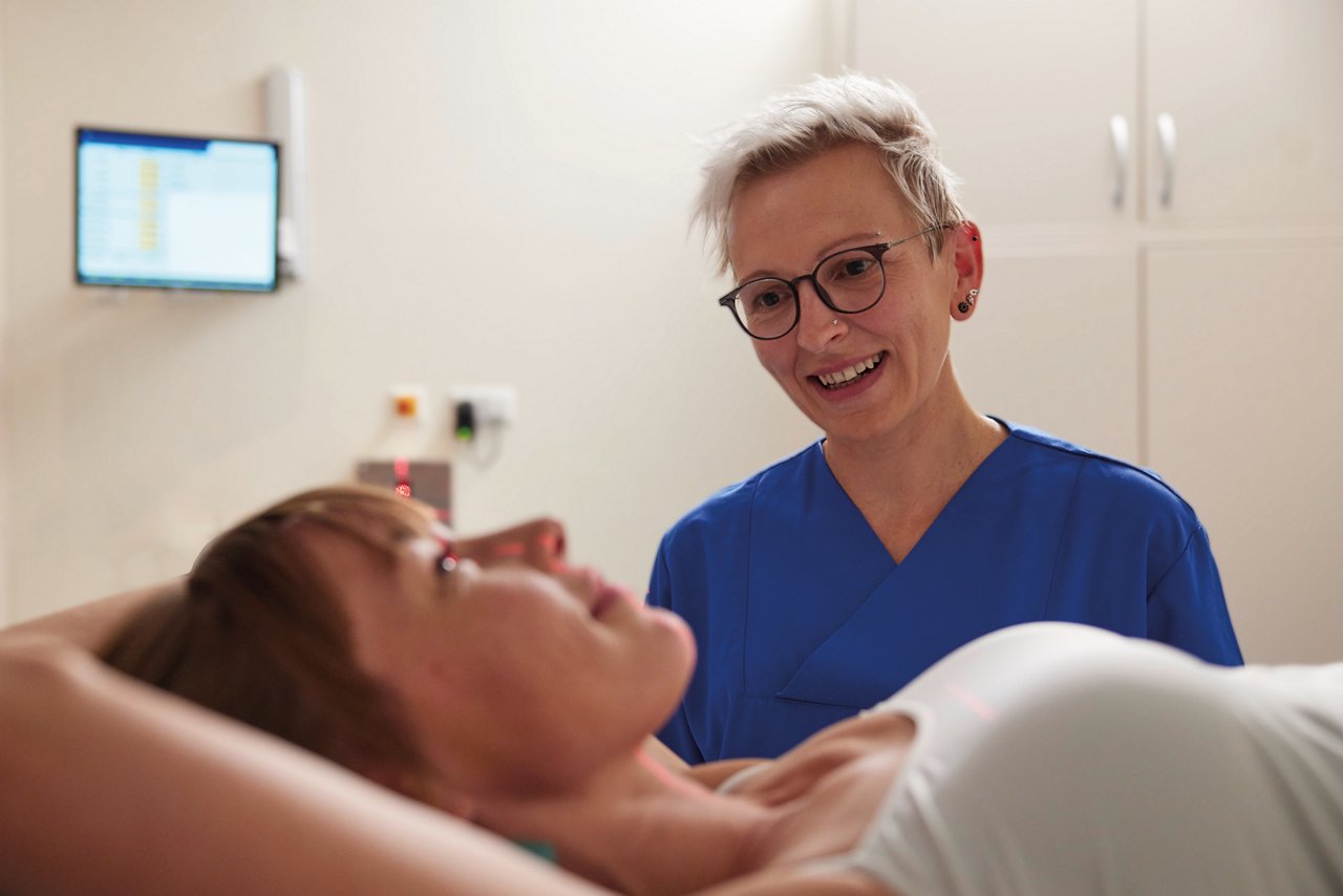 Eine ILD Patientin wird während der Untersuchung freundlich begleitet von einer jungen Pflegfachkraft