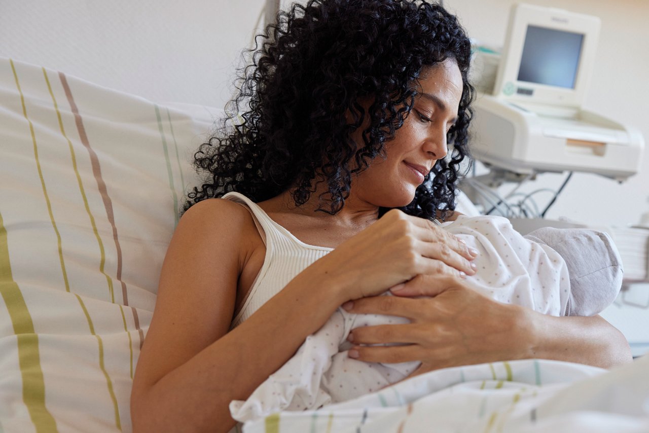 Mutter mit neugeborenem Baby auf der Wöchnerinnen-Station im Bett