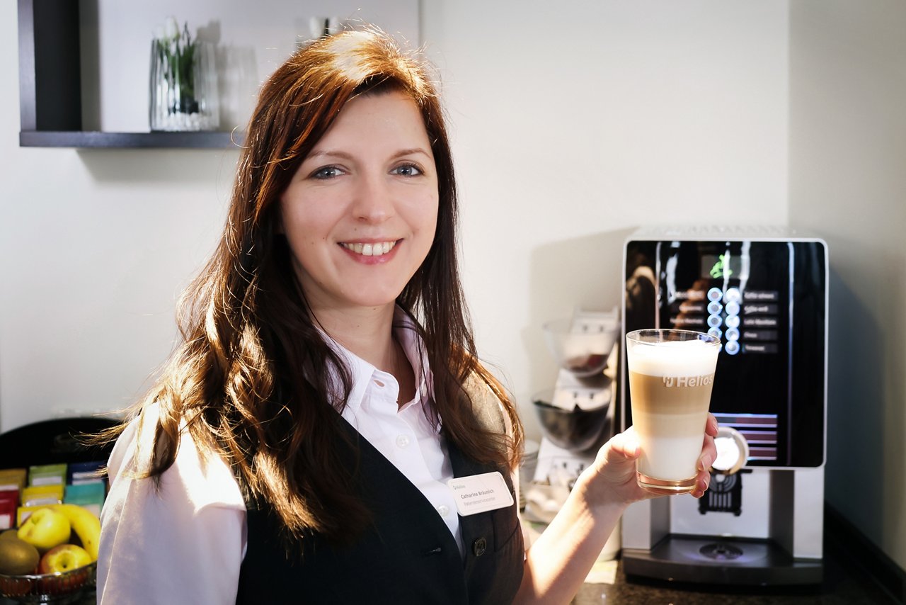 Mitarbeiterin mit Latte Macchiato aus dem Kaffeeautomat