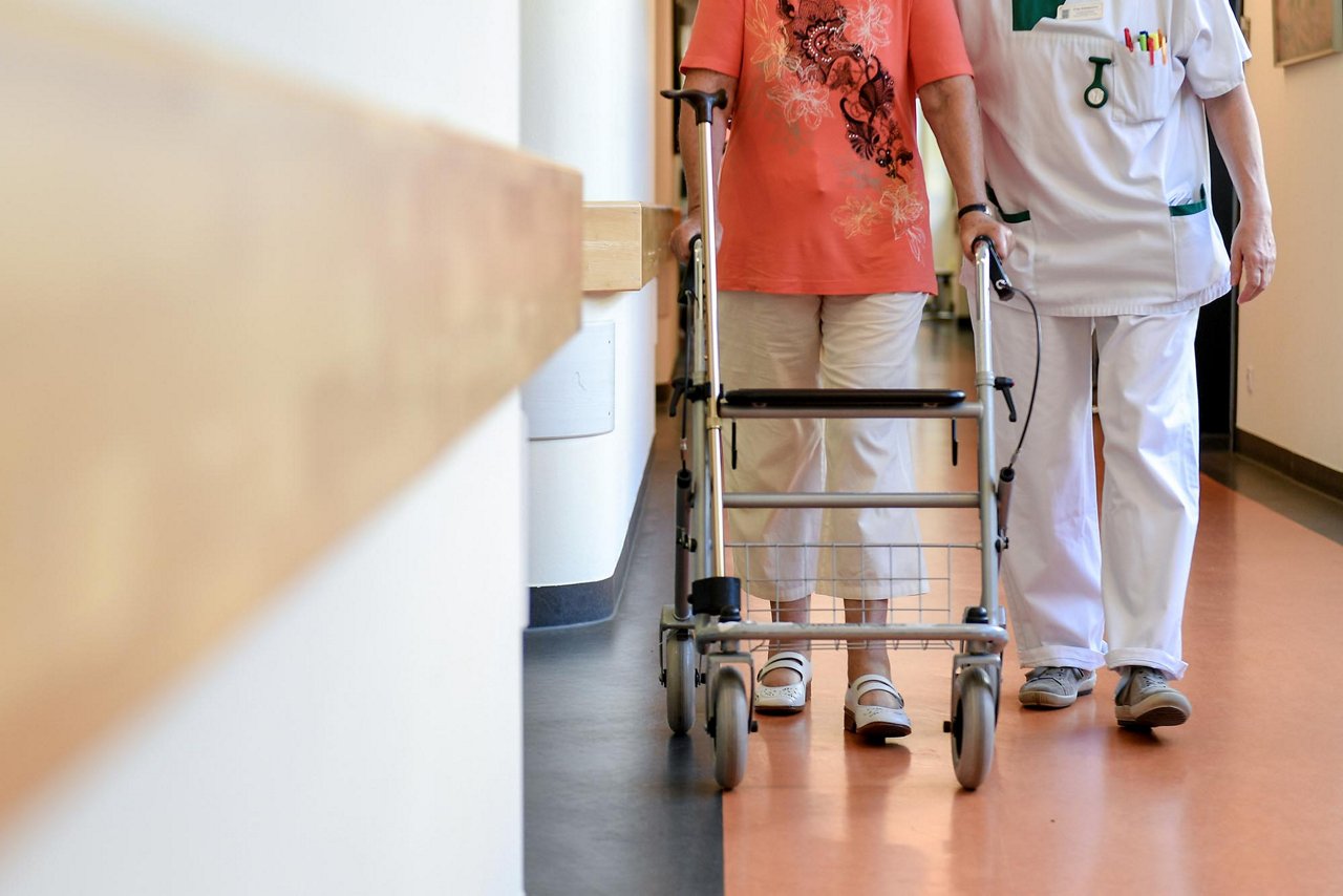 A specially trained nurse provides support to an elderly woman on a corridor of a hospital in Schwelm, Germany, 30 July 2018. The official July figures will be announced by the Federal Employment Agency on 31 July. Experts expect unemployment to rise slightly by 46,000 people without jobs to around 2.32 million at the start of the summer break, around 196,000 less than a year ago.