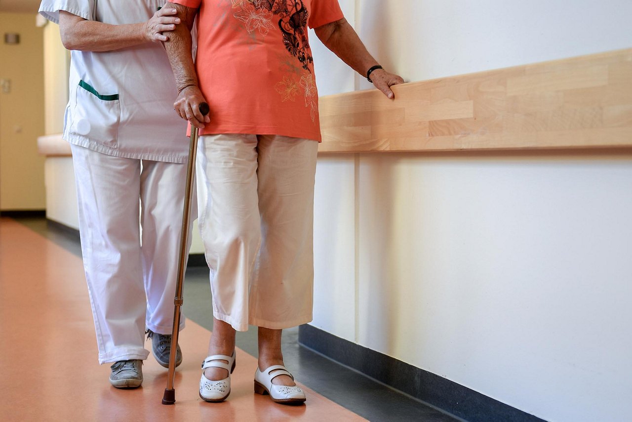 A specially trained nurse provides support to an elderly woman on a corridor of a hospital in Schwelm, Germany, 30 July 2018. The official July figures will be announced by the Federal Employment Agency on 31 July. Experts expect unemployment to rise slightly by 46,000 people without jobs to around 2.32 million at the start of the summer break, around 196,000 less than a year ago.