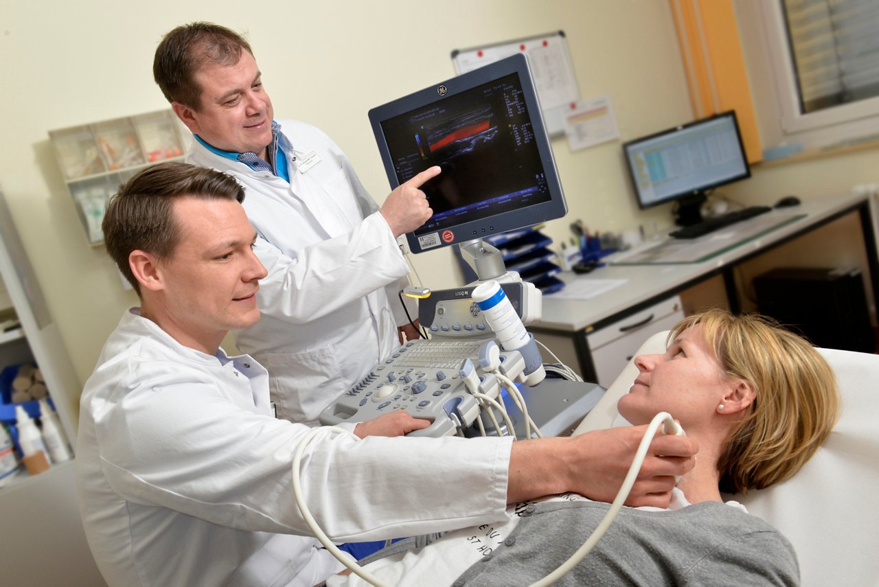 Ein Arzt untersucht die Gefäße am Hals per Ultraschall