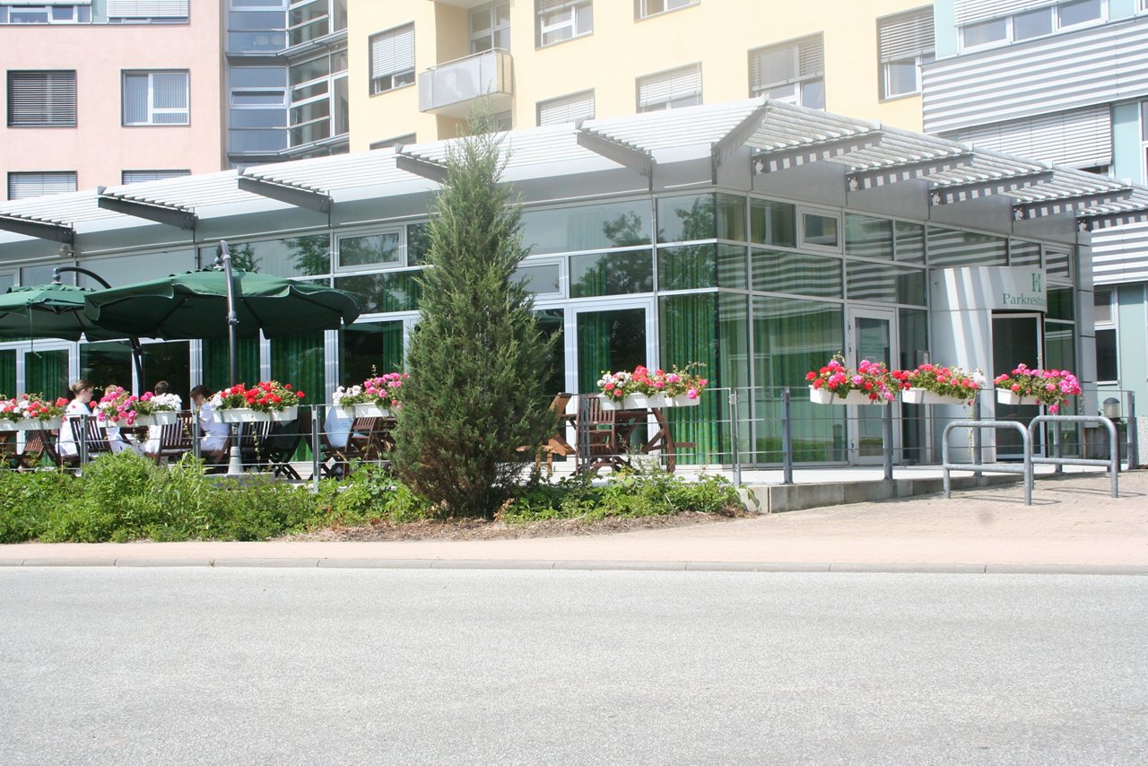 Außengelände des Parkrestaurants mit Terrasse, Stühlen und Blumen