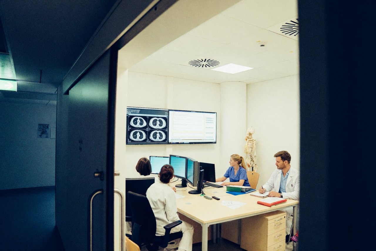 Vier Ärzte sitzen zur Tumorkonferenz und betrachten Bilder