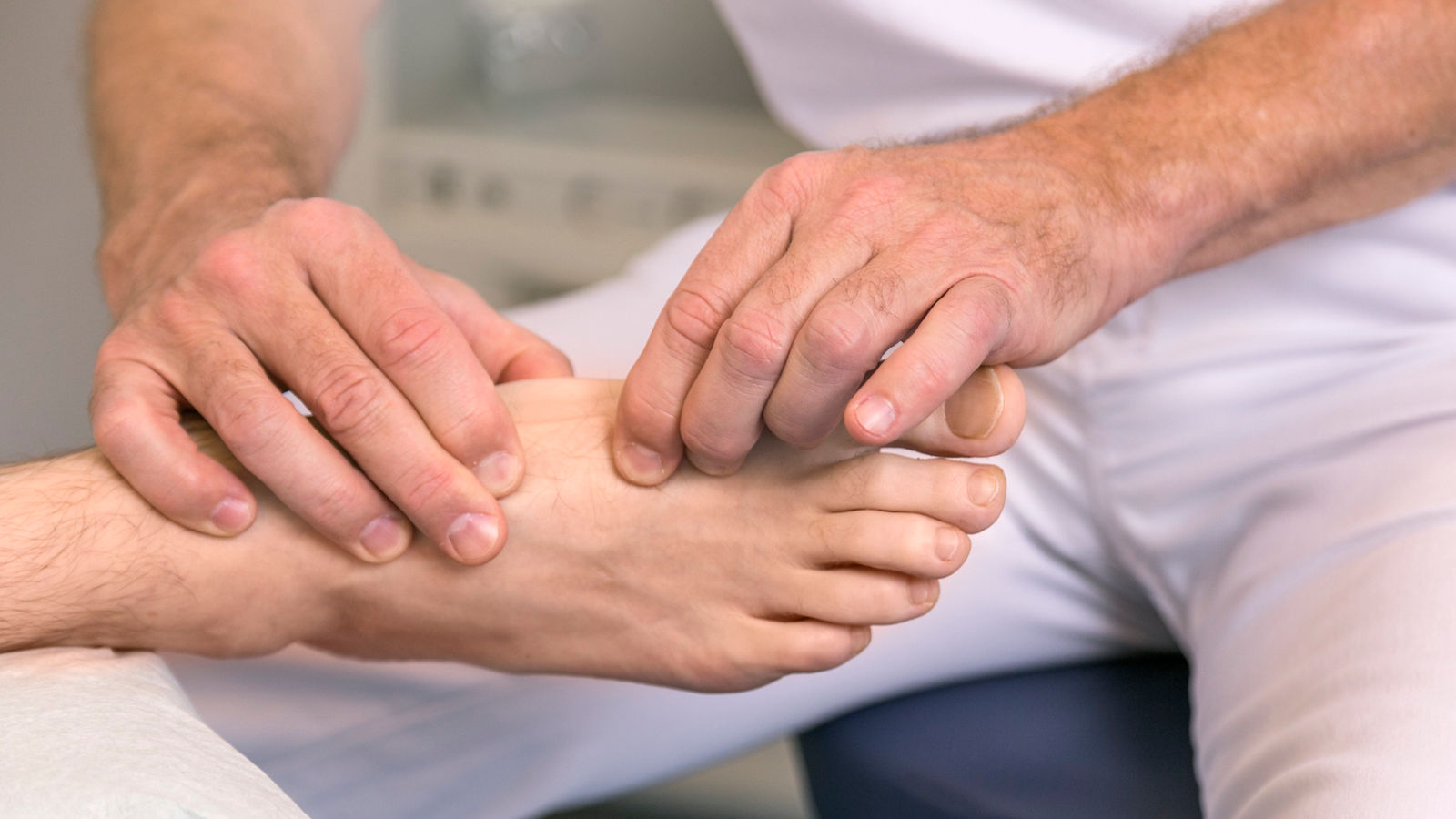Professionelle Fußuntersuchung zur Diagnose und Behandlung von Fußproblemen. Expertenhand greift sanft den Fuß, um Schmerzen und Beschwerden zu identifizieren.