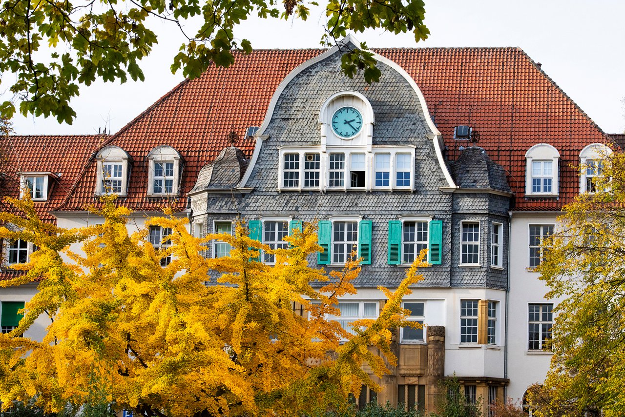 Blick auf das Eingangsgebäude mit Torbogen am Campus Barmen im Herbst