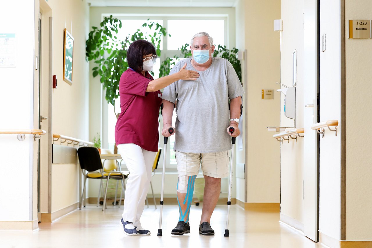 Physiotherapeutin bei der Behandlung eines Patienten mit Knieprothese 2