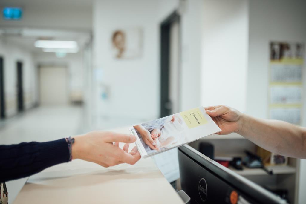 Pflegekraft übergibt Flyer an Patientin