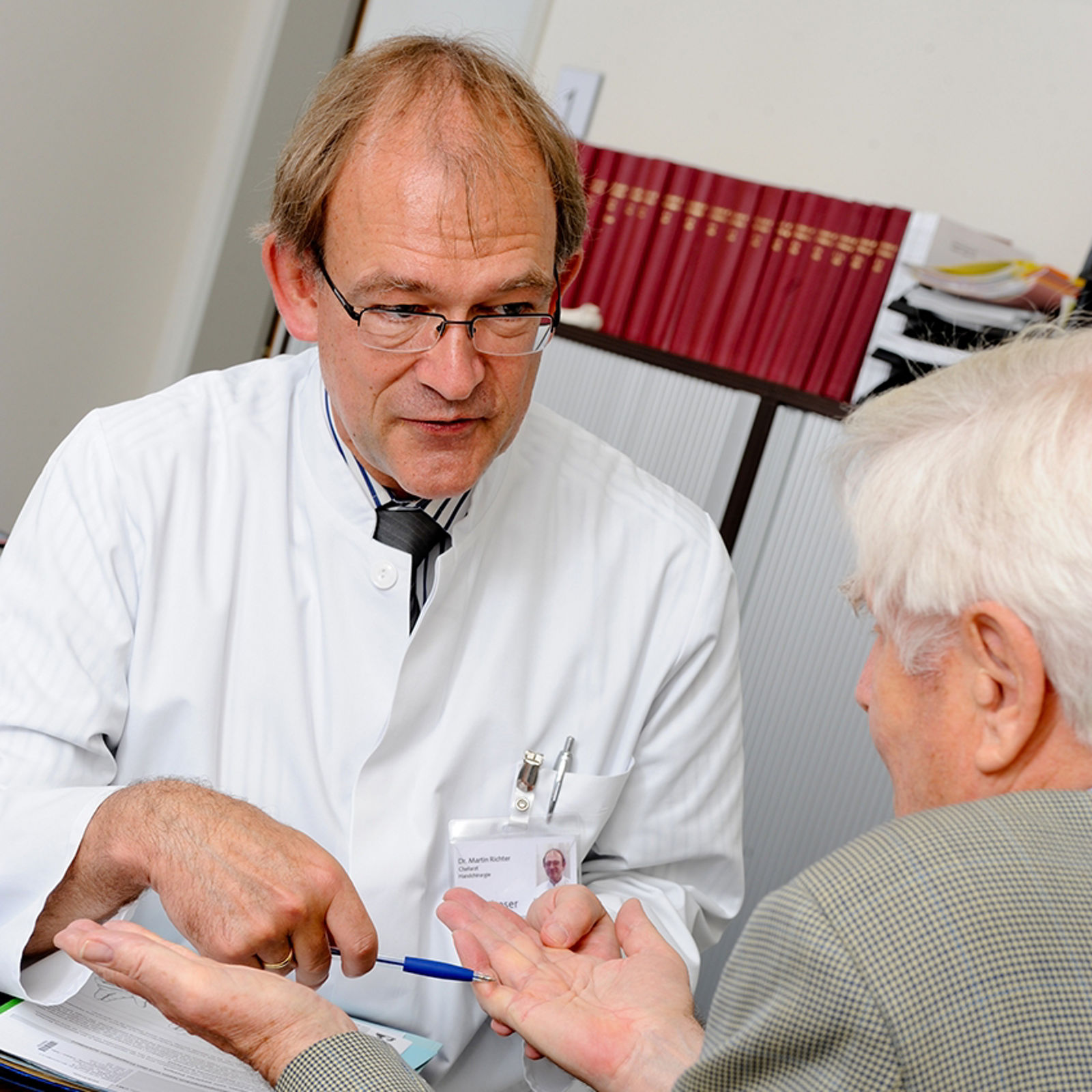 Arzt erklärt Patient Handchirurgie 