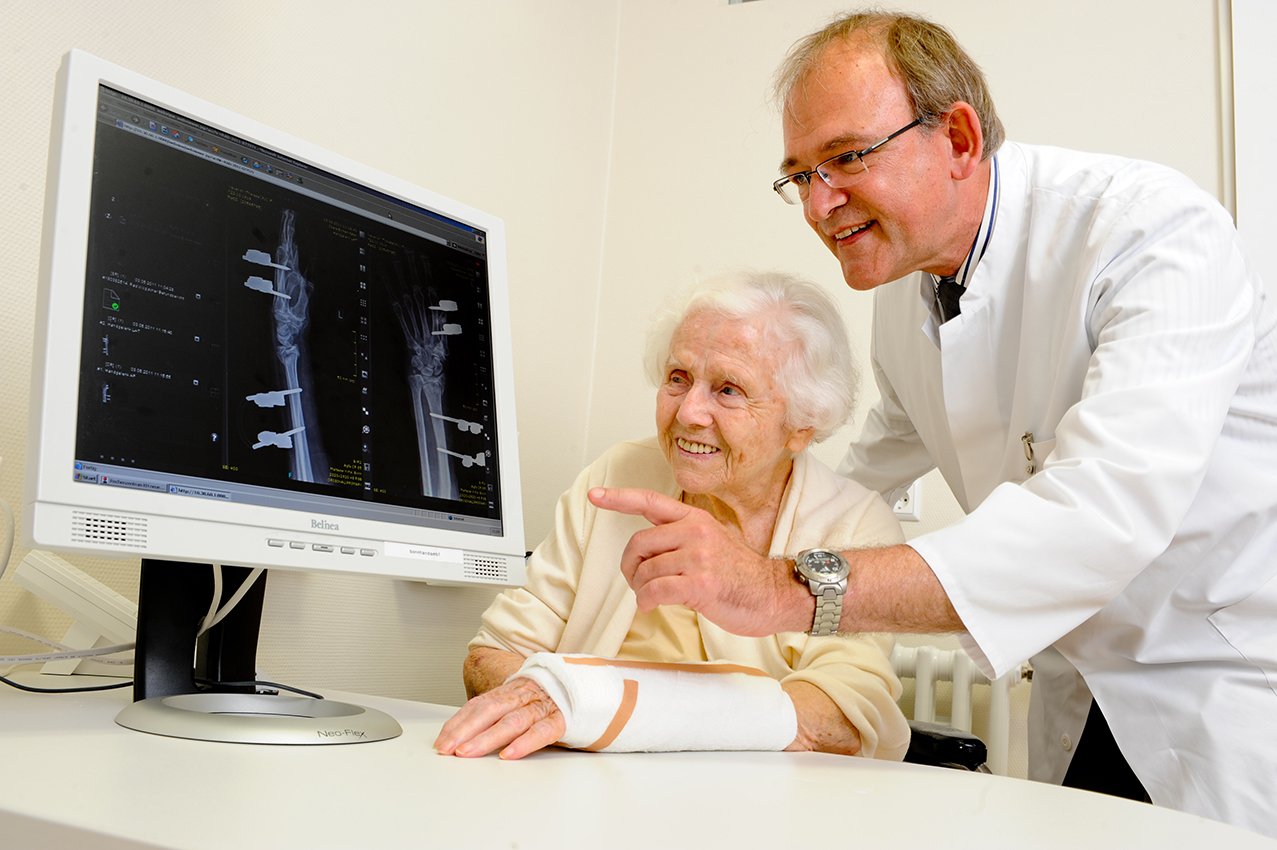 Arzt erklärt Patientin Röntgenbild auf Computer