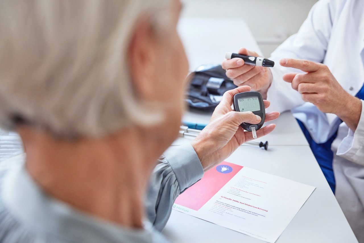 Close up von Hände Arzt mit Stechhilfe und Frau Hände hält Glukose-Messgerät für Diabetes-Tester Blutzuckerspiegel Patientenkampagne 2022