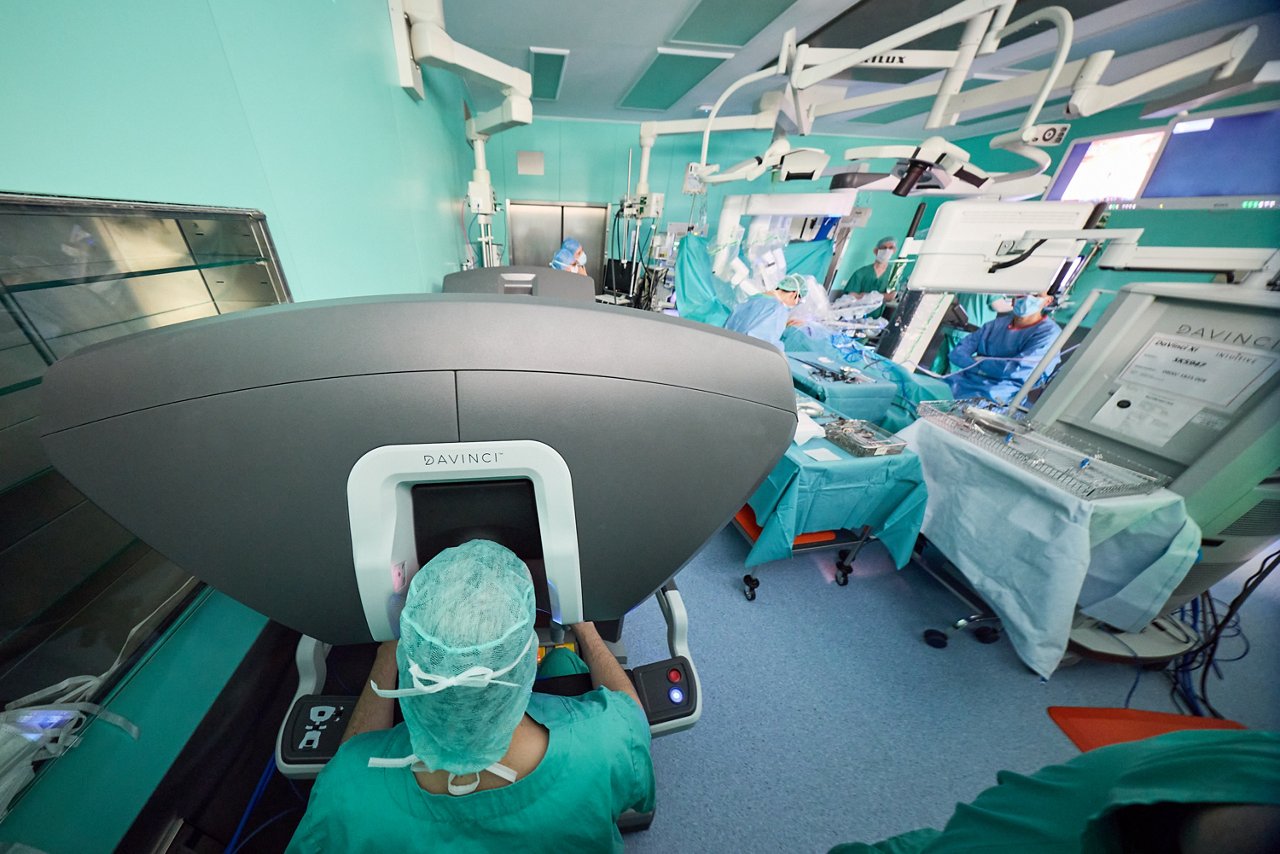 Ein Operationssaal, in dem ein Arzt am Da-Vinci-Operationssystem sitzt.
