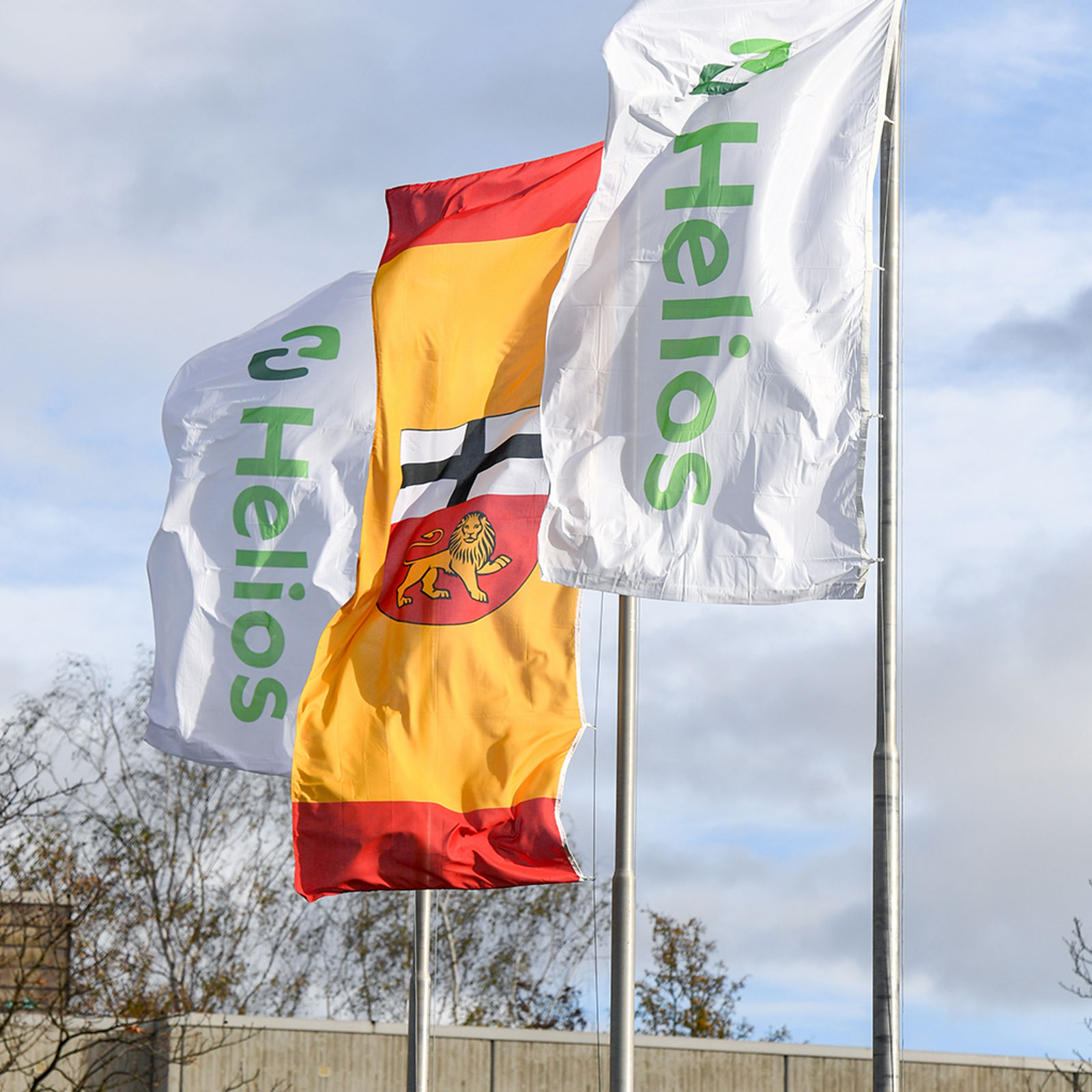 Helios-Fahnen und Bonn-Fahnen wehen im Wind vor dem Klinikgebäude 