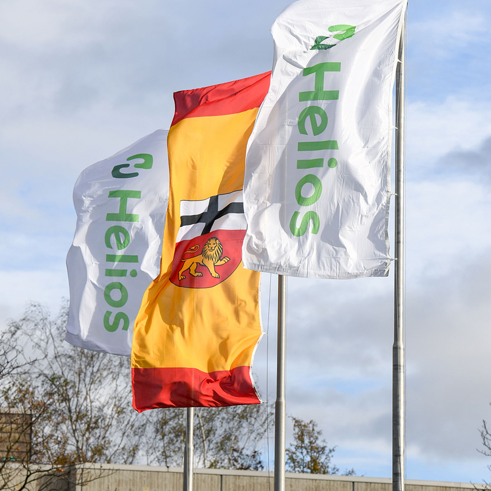 Helios-Fahnen und Bonn-Fahnen wehen im Wind vor dem Klinikgebäude 
