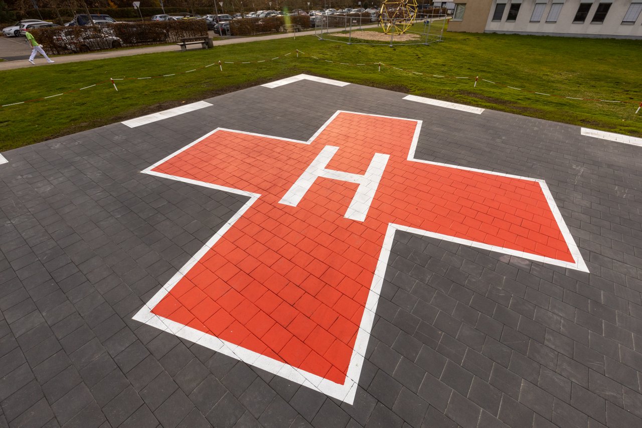 Hubschrauberlandeplatz  mit einem großen roten Kreuz und Buchstabe H auf dem Boden. 