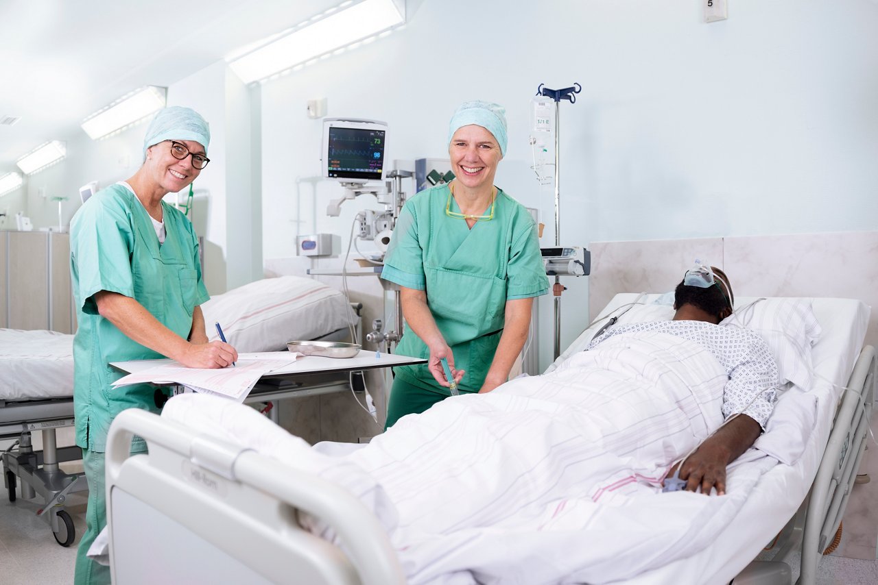 Zwei ATA-Pflegekräfte stehen am Patientenbett mit FFP2-Maske .