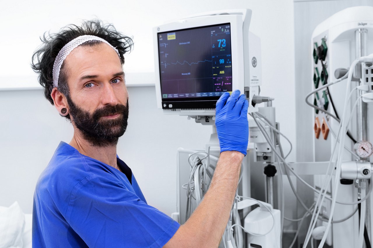 Intensivpflegekraft bedient mit Handschuhen Überwachungsmonitor 