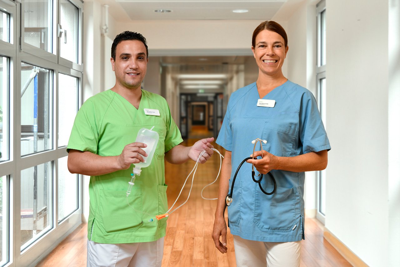 KlinikFIT Pflegerin und Pfleger im Flur mit Equipment