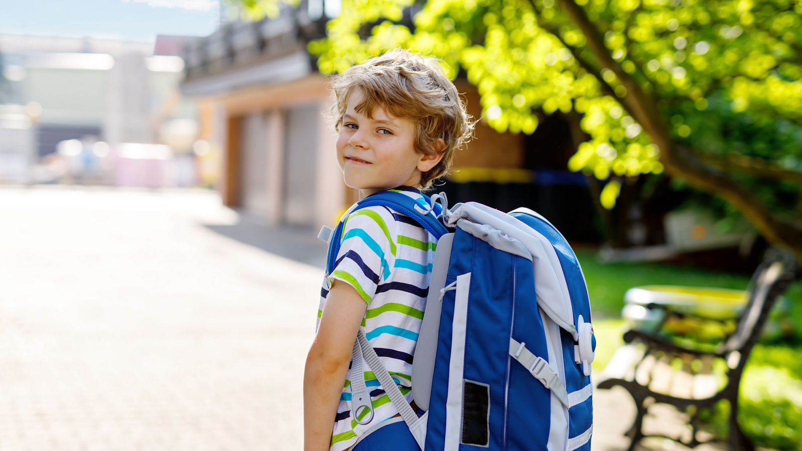 little kid boy with school satchel on first day to school