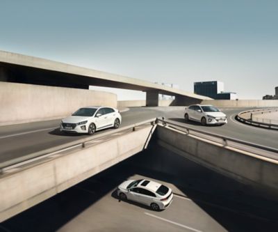 Two white Hyundai IONIQ sedans driving on a bridge.