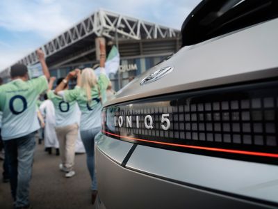 Hyundai IONIQ 5 na snímku s jásajícími fotbalovými fanoušky na cestě na stadion.