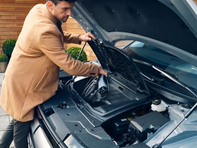 A man grabs the charging cable from the frunk in the front of his Hyundai IONIQ 5.