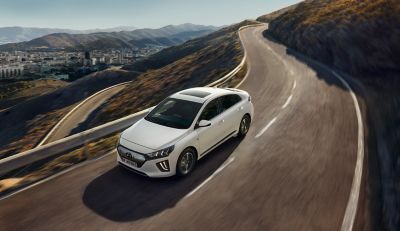 Nový Hyundai IONIQ Electric jedoucí po silnici v horách.