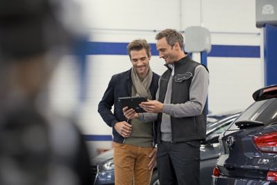 A Service consultant explains the work to the customer on a tablet.