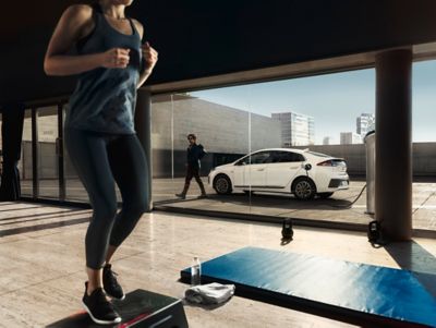 Afbeelding van een sportende vrouw met een geparkeerde Hyundai IONIQ Electric op de achtergrond.