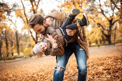 Ojciec i dziecko bawią się jesienią w parku