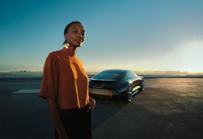 Hyundai IONIQ 6 concept car parked behind a woman confidently looking into the future.