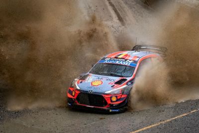 The Hyundai i20 Coupe WRC driving through a lot of mud.