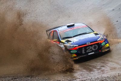 Voiture de rallye customer racing Hyundai Motorsport i20 R5 éclaboussant de l’eau des deux côtés.