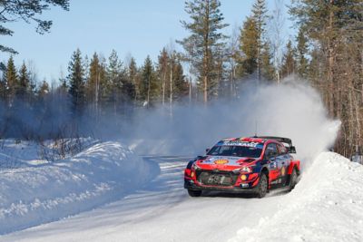 Hyundai Motorsport i20 Coupe WRC driftant dans un virage laissant derrière lui des nuages de neige