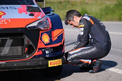 Hyundai motorsport driver Dani Sordo checking the wheel of his i20 N.