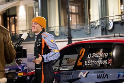 Hyundai Motorsport driver Oliver Solberg getting interviewed in front of his rally car.
