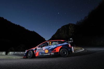 Hyundai Motorsport driver Oliver Solberg's i20 N WRC Rally1 driving around a sharp corner at night.