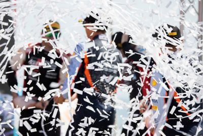 Hyundai Motorsport drivers standing in a rain of confetti in celebration of a victory.