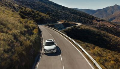 Nový Hyundai IONIQ Electric jedoucí po silnici v horách.