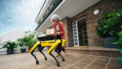 Le robot de Boston Dynamics Spot livre un colis à une femme âgée.